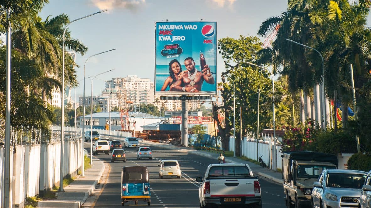 A Pepsi billboard between palm trees on a main road in Dar es Salaam