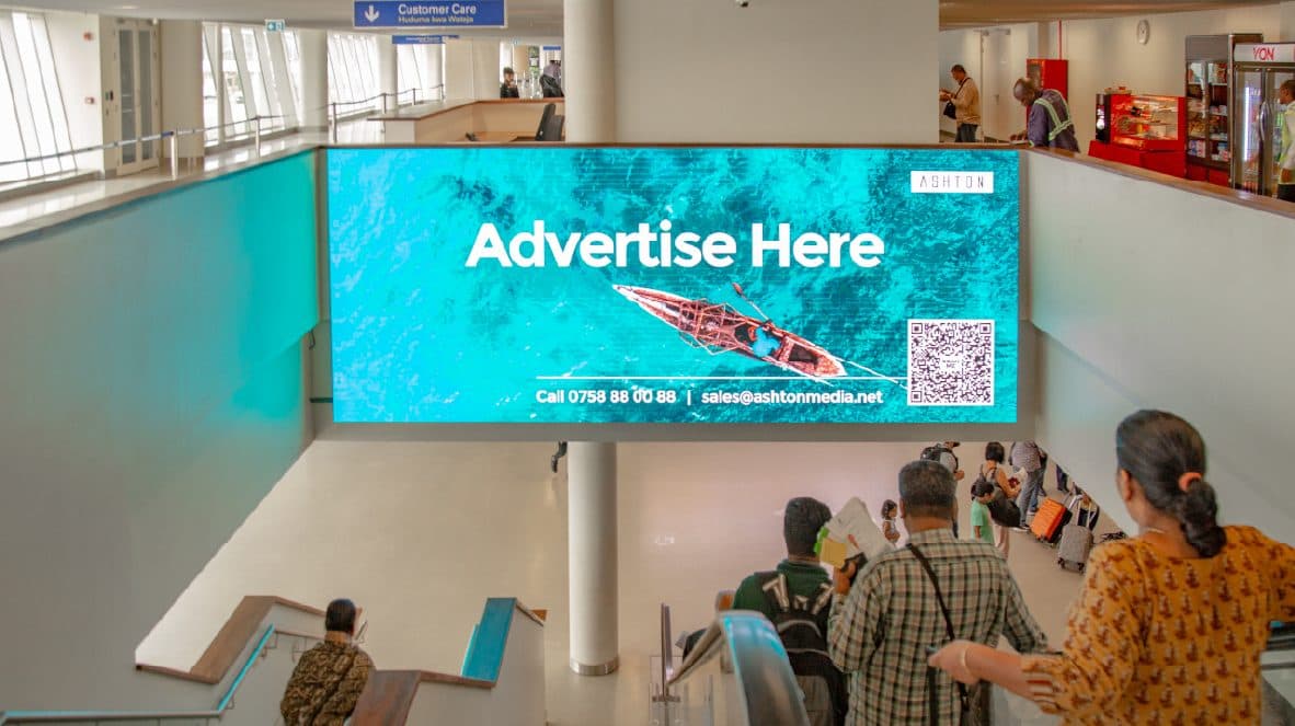 A digital screen above the airport escalators
